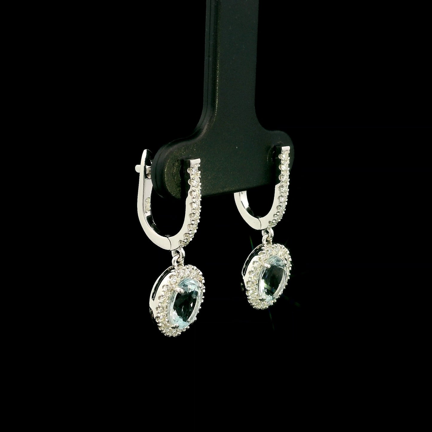 18K White Gold Aquamarine Drop Earrings featuring 1.50 carats of natural oval aquamarines surrounded by diamond halos with diamond huggie hoops and 0.48 carat natural diamonds.
