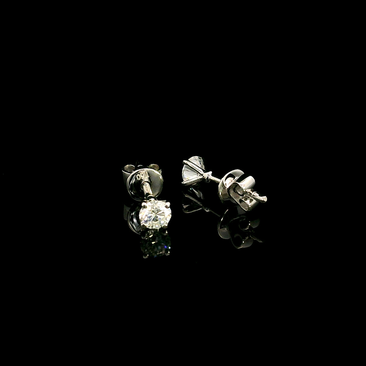 Diamond solitaire stud earrings in 18K white gold featuring round brilliant diamonds in classic four-prong settings.
