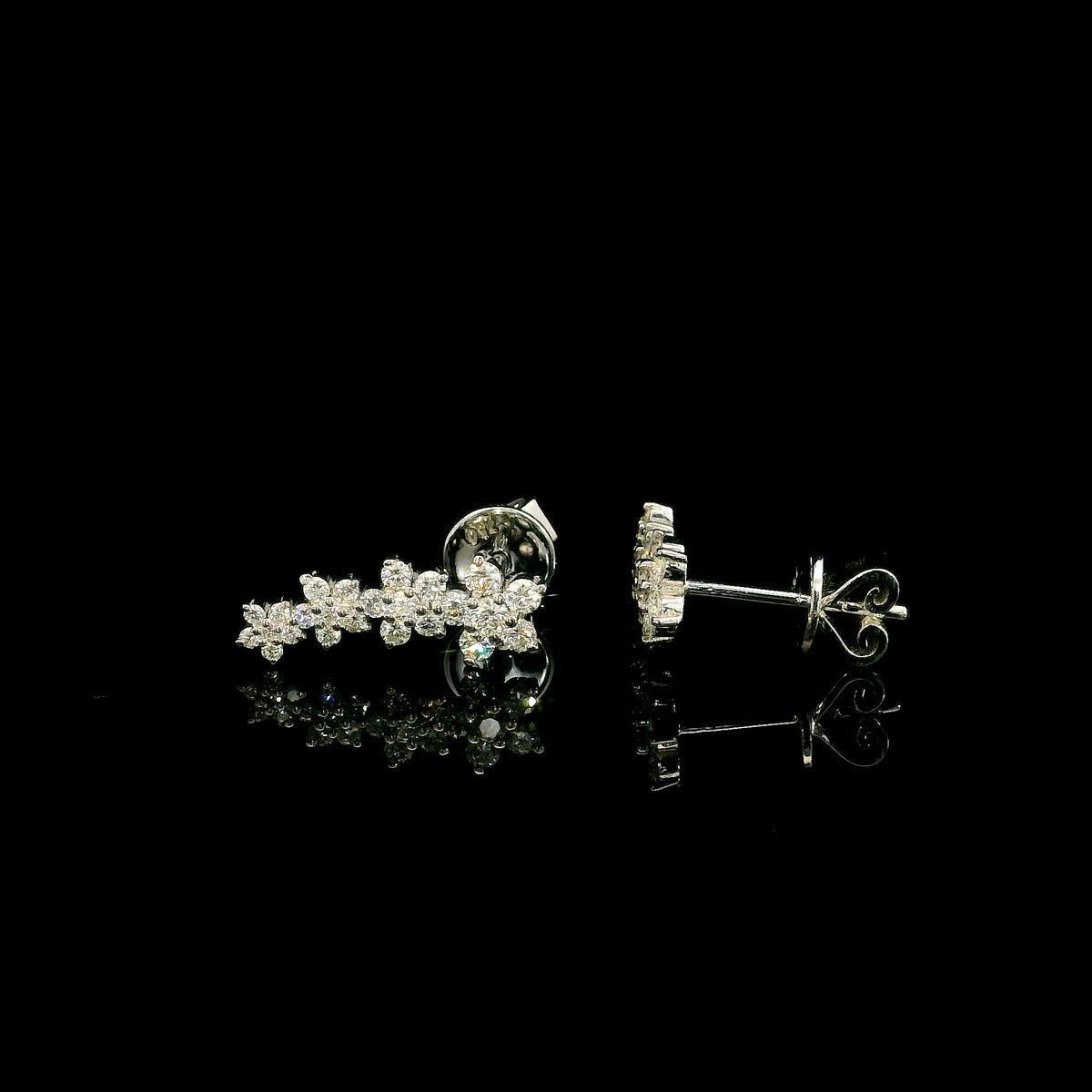 Diamond floral ear climber earrings in 18K white gold with graduating round diamond flower clusters designed to follow the ear.