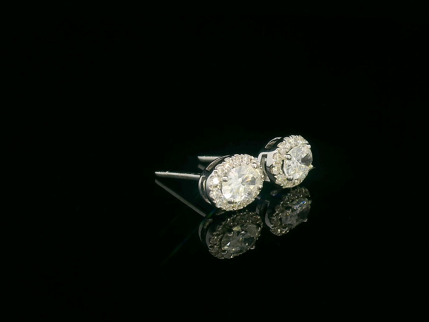 Oval diamond halo stud earrings in 18K white gold with 0.49 carats total diamond weight