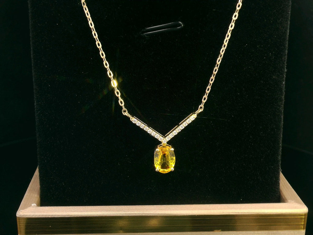 Yellow sapphire and diamond necklace in 18K yellow gold featuring a 1.01 carat oval yellow sapphire suspended beneath a V-shaped arrangement of round diamonds.
