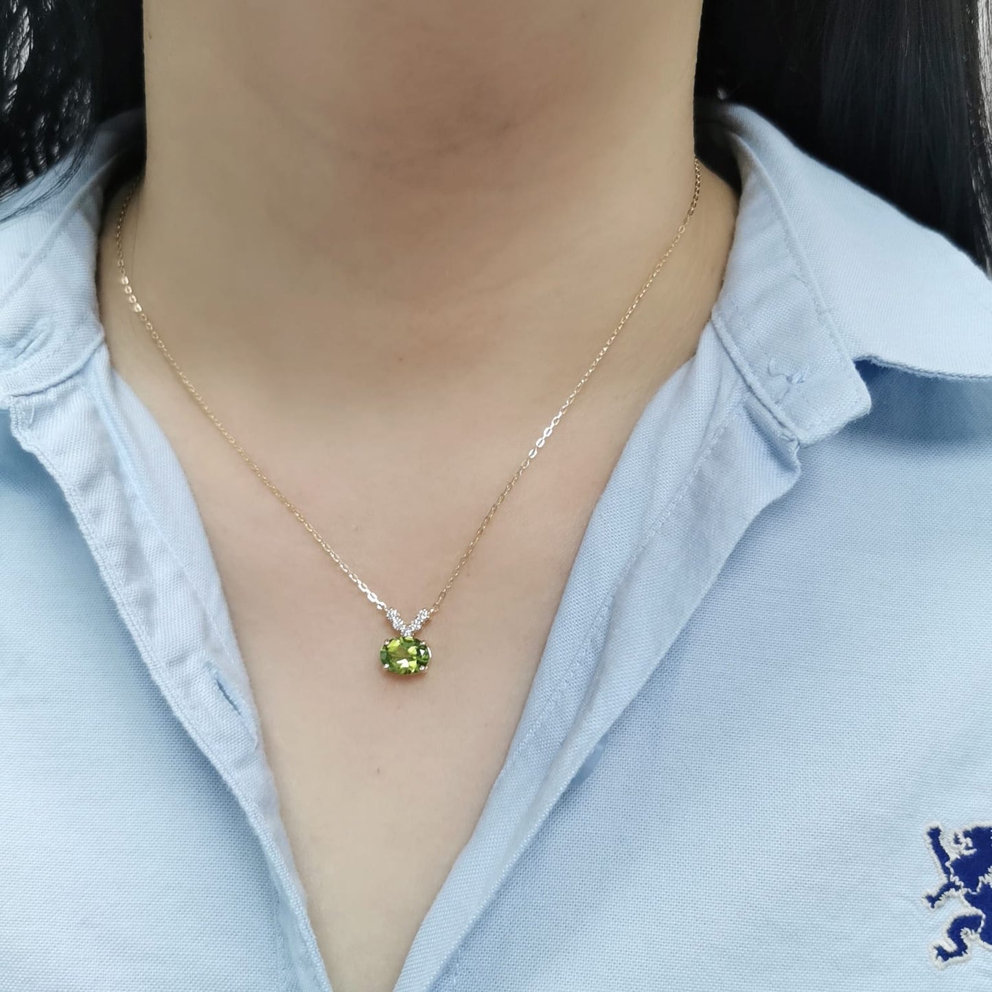 18K gold necklace featuring a 1.68-carat oval Peridot pendant with a 0.15-carat diamond cluster accent in a V-shape, suspended from a fine gold chain.
