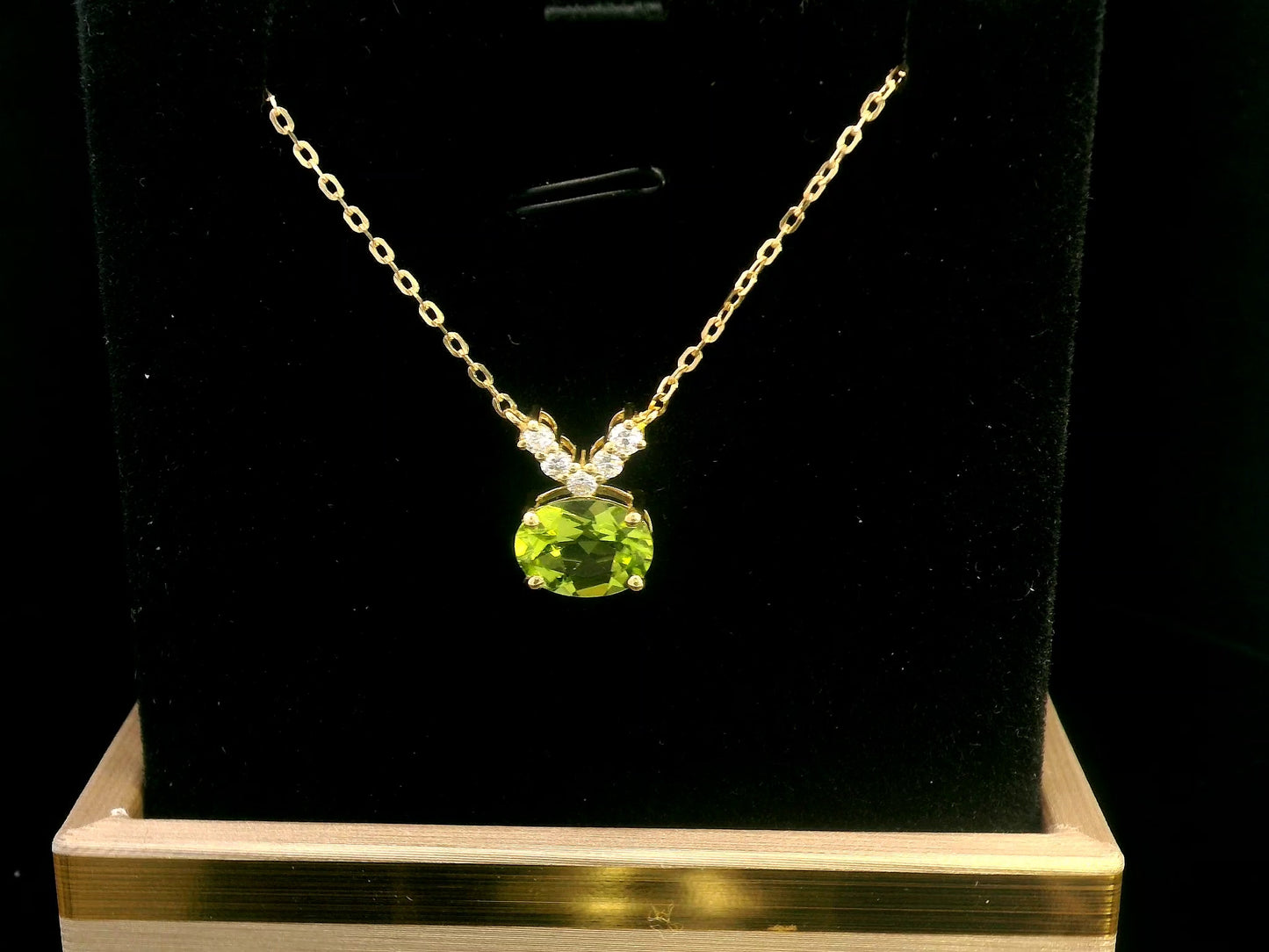 18K gold necklace featuring a 1.68-carat oval Peridot pendant with a 0.15-carat diamond cluster accent in a V-shape, suspended from a fine gold chain.