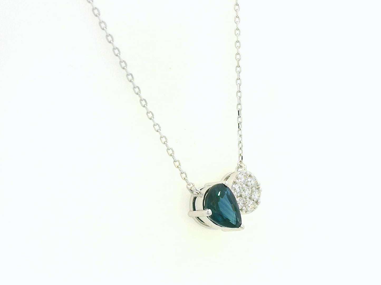 18K white gold pendant featuring a 0.97 carat pear-cut blue sapphire and 0.17 carat round diamond cluster on a fine gold chain.