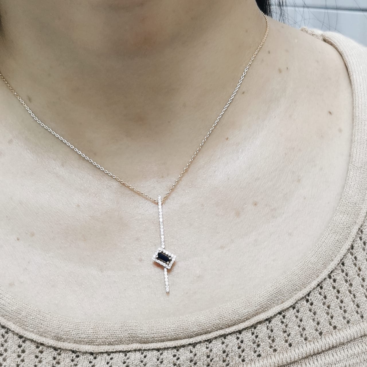 18K gold pendant with vertical diamond bar and tilted halo-set 0.19 carat blue sapphire