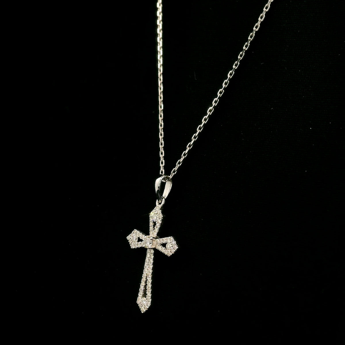 Diamond cross pendant in 18K white gold with round diamonds, an openwork design and distinctive pointed ends.