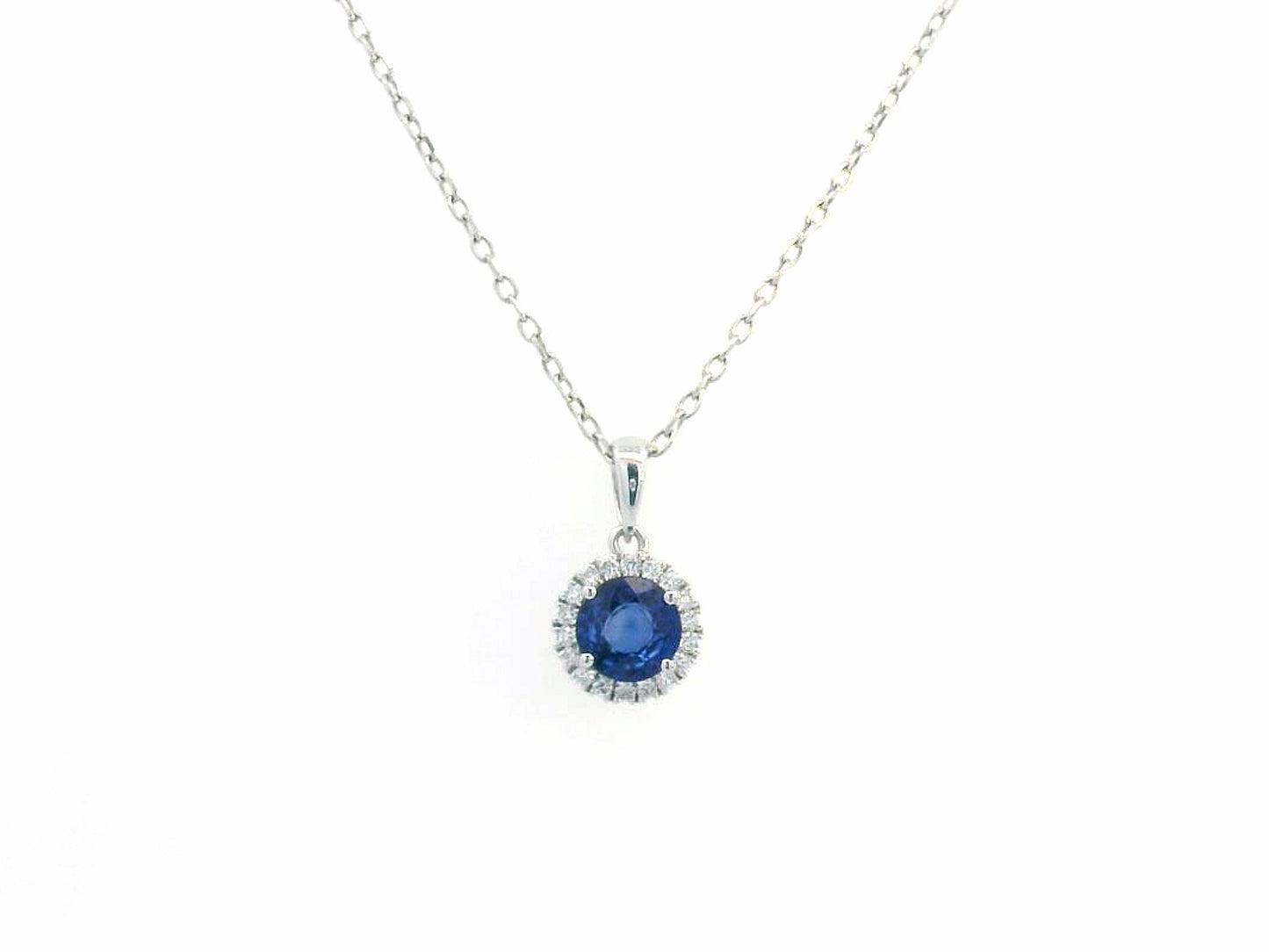 "18K white gold sapphire and diamond halo pendant featuring a 0.72ct deep blue sapphire surrounded by a 0.10ct diamond halo,