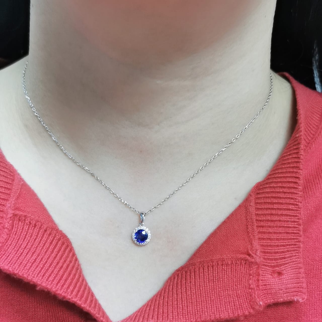 "18K white gold sapphire and diamond halo pendant featuring a 0.72ct deep blue sapphire surrounded by a 0.10ct diamond halo,
