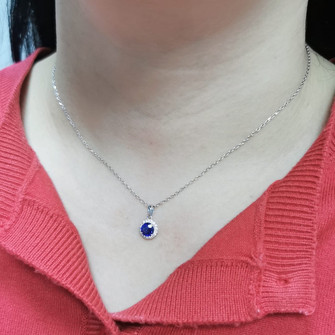 "18K white gold sapphire and diamond halo pendant featuring a 0.72ct deep blue sapphire surrounded by a 0.10ct diamond halo,