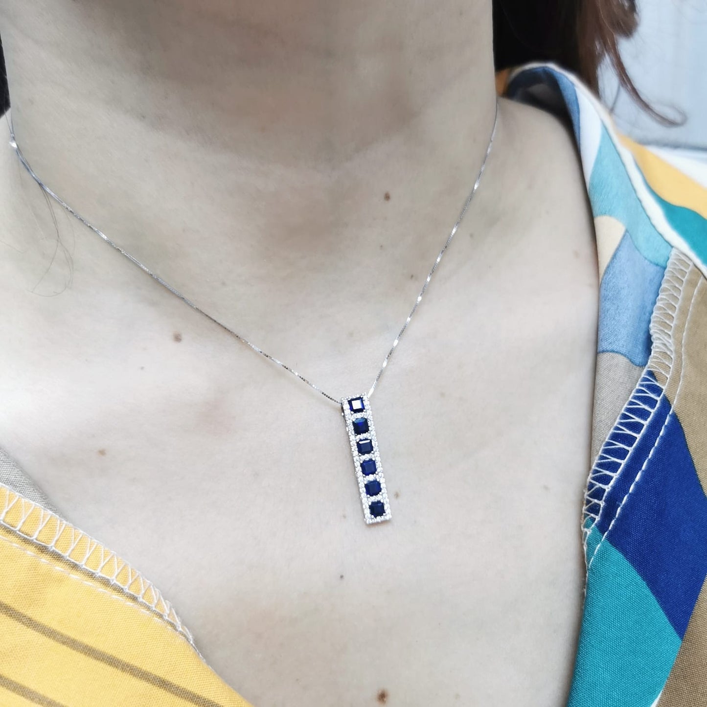 18K Yellow Gold Sapphire and Diamond Pendant featuring 1.45 carats of square-cut sapphires and a 0.34-carat diamond halo in a sleek vertical design.