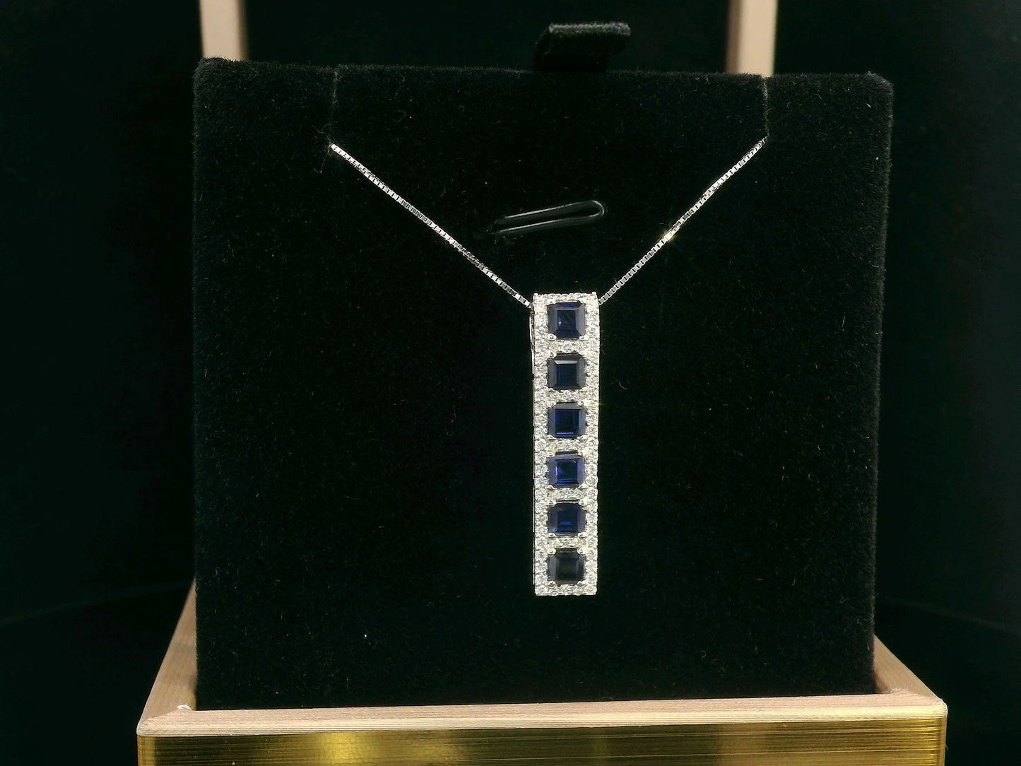 18K Yellow Gold Sapphire and Diamond Pendant featuring 1.45 carats of square-cut sapphires and a 0.34-carat diamond halo in a sleek vertical design.