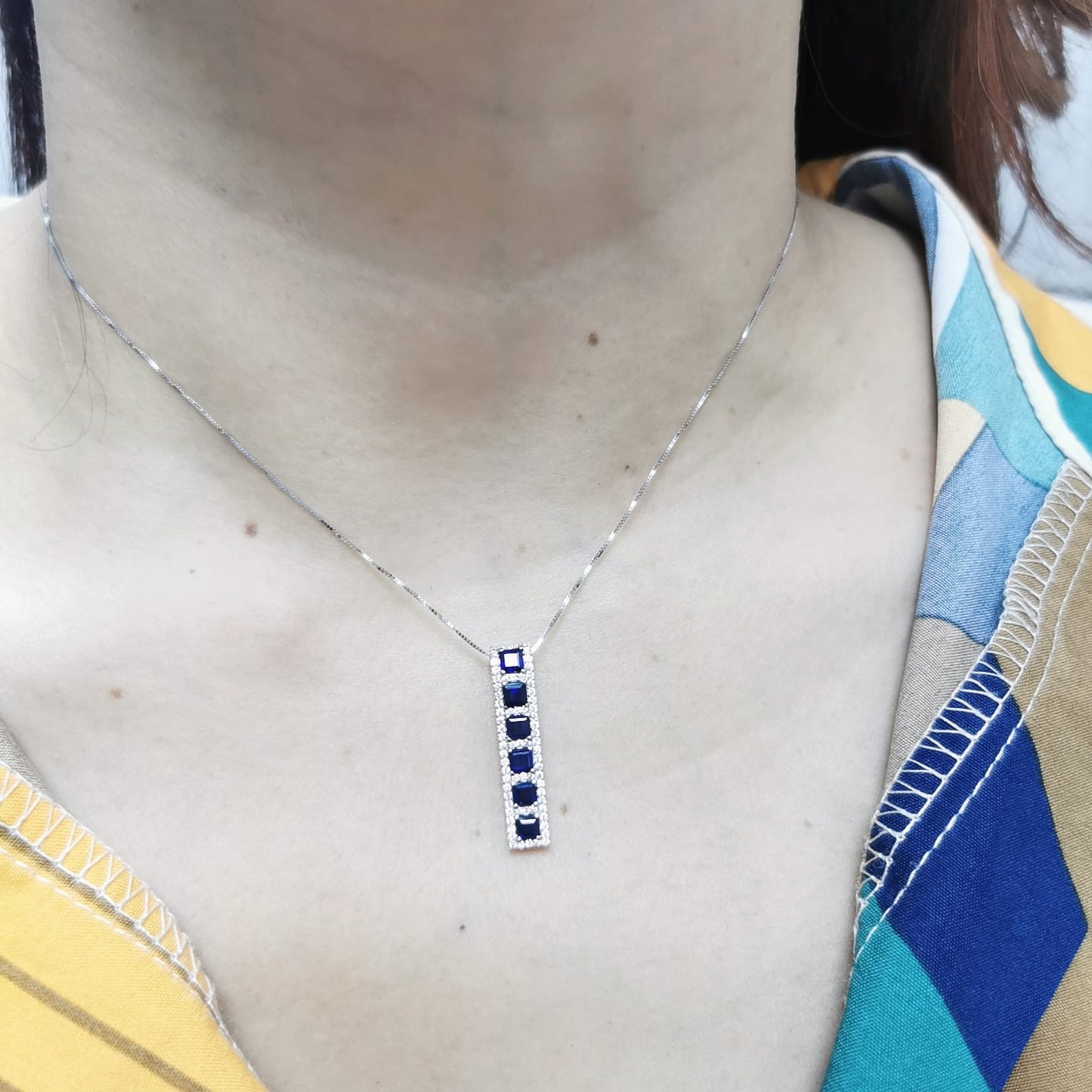 18K Yellow Gold Sapphire and Diamond Pendant featuring 1.45 carats of square-cut sapphires and a 0.34-carat diamond halo in a sleek vertical design.