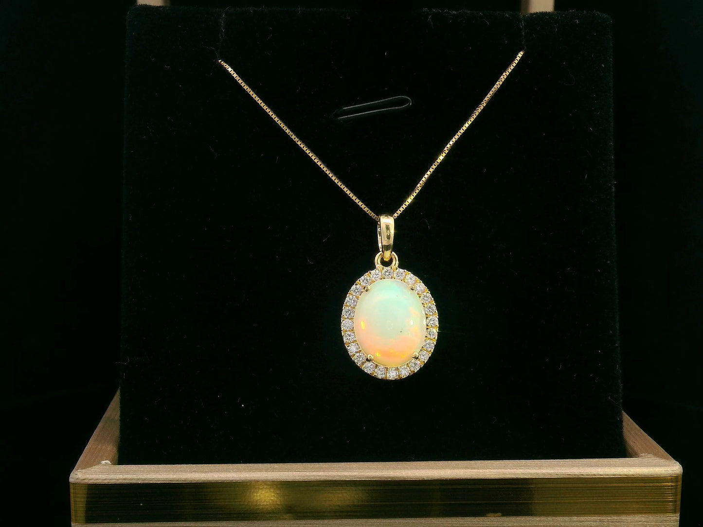 Elegant 18K gold opal and diamond halo pendant featuring a 1.68-carat opal gemstone surrounded by a sparkling 0.28-carat diamond halo.