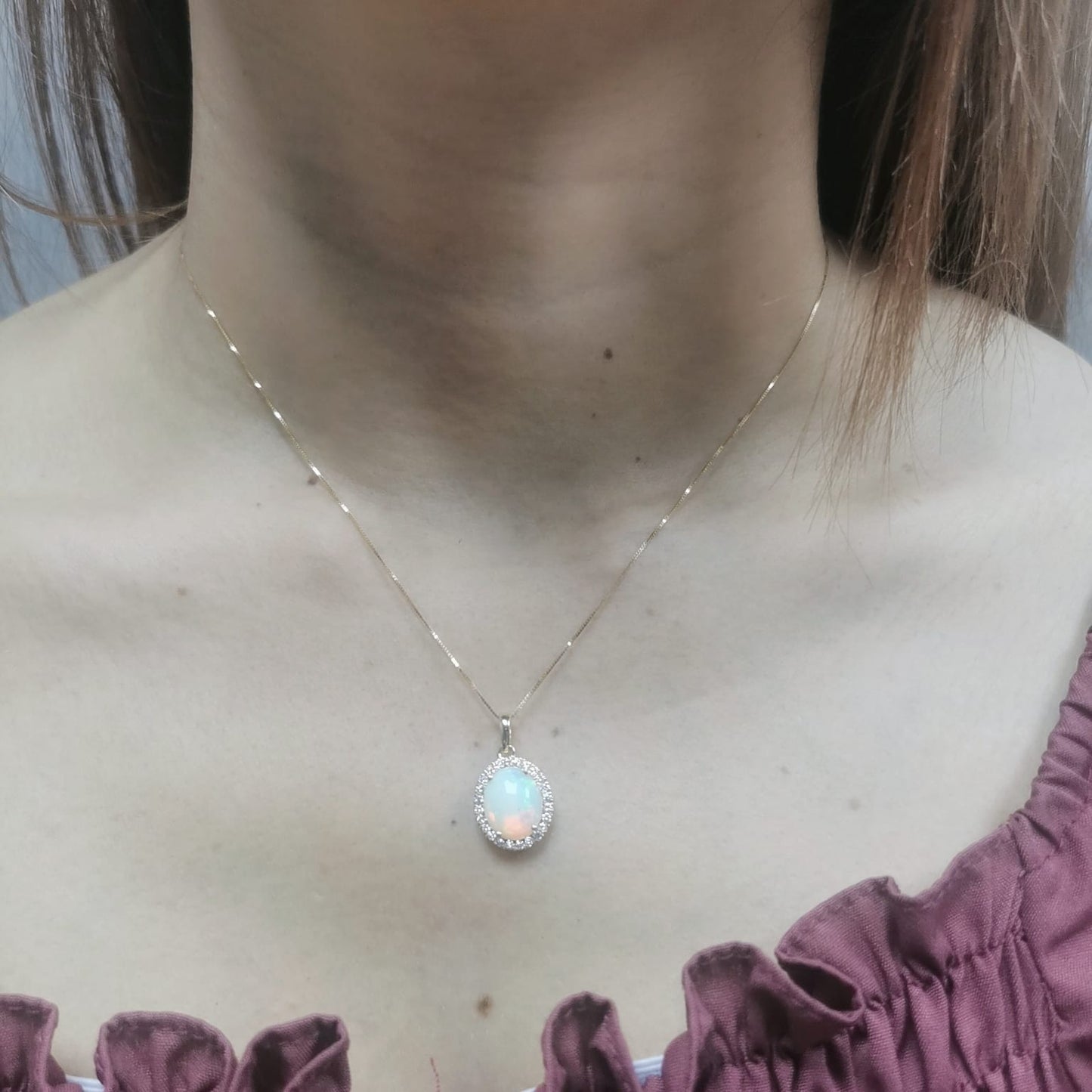Elegant 18K gold opal and diamond halo pendant featuring a 1.68-carat opal gemstone surrounded by a sparkling 0.28-carat diamond halo.