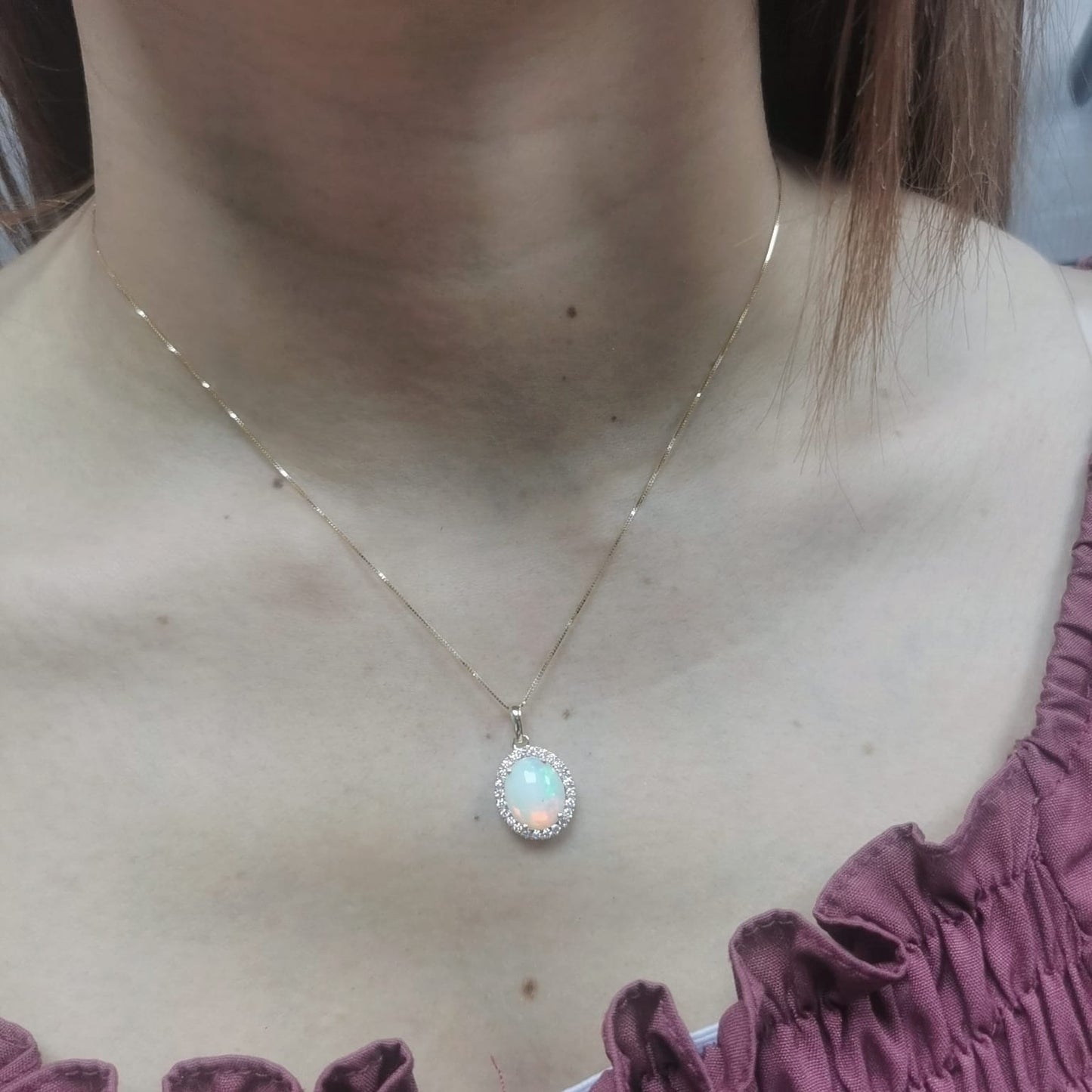 Elegant 18K gold opal and diamond halo pendant featuring a 1.68-carat opal gemstone surrounded by a sparkling 0.28-carat diamond halo.