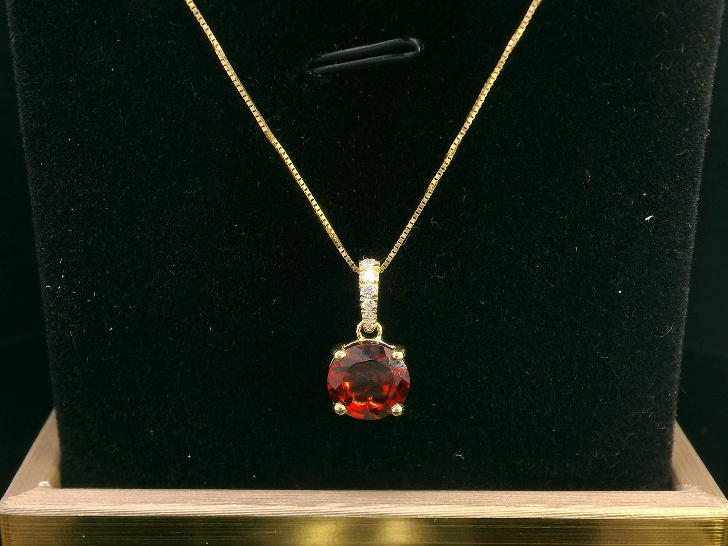 18K gold pendant with a 2.03ct deep red garnet in a four-prong setting, accented by 0.06ct diamonds on the bail. Chain not included.