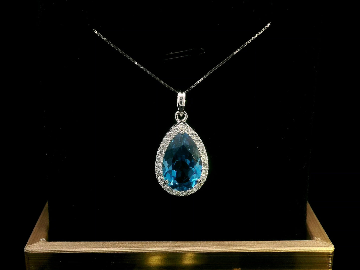 18K white gold pendant with a 5.87ct pear-shaped London Blue Topaz, surrounded by a 0.33ct diamond halo. Chain not included.