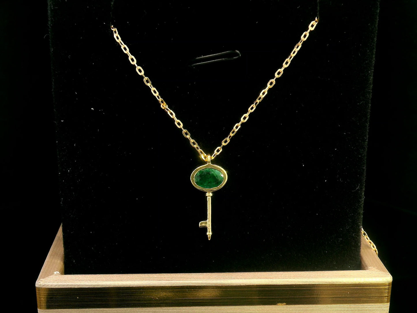 18K gold key pendant necklace with a 0.39ct natural emerald, featuring a sleek bezel setting and a delicate gold chain.