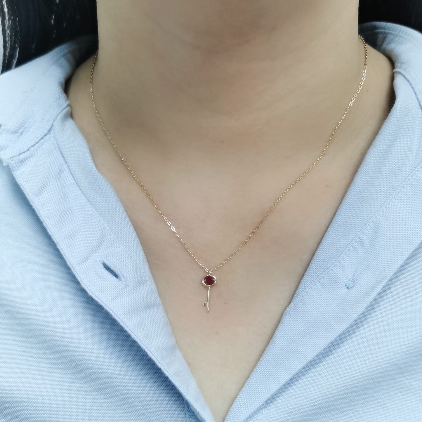 18K gold key pendant necklace with a 0.39ct natural ruby, featuring a sleek bezel setting and a delicate gold chain.