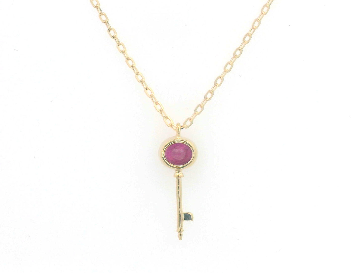 18K gold key pendant necklace with a 0.39ct natural ruby, featuring a sleek bezel setting and a delicate gold chain.