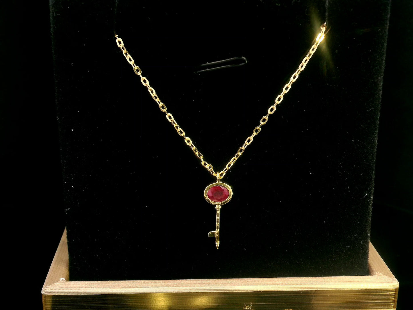 18K gold key pendant necklace with a 0.39ct natural ruby, featuring a sleek bezel setting and a delicate gold chain.