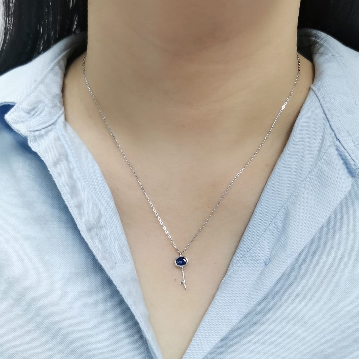 18K gold key pendant necklace with a 0.40ct natural sapphire in a bezel setting, complete with a delicate gold chain.