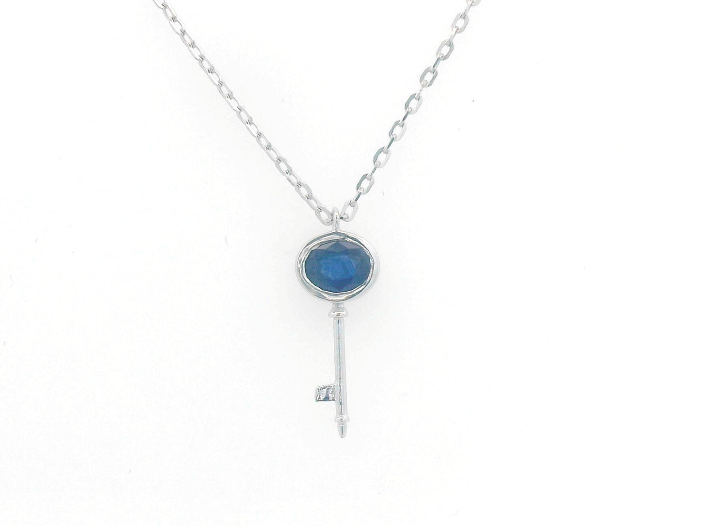 18K gold key pendant necklace with a 0.40ct natural sapphire in a bezel setting, complete with a delicate gold chain.