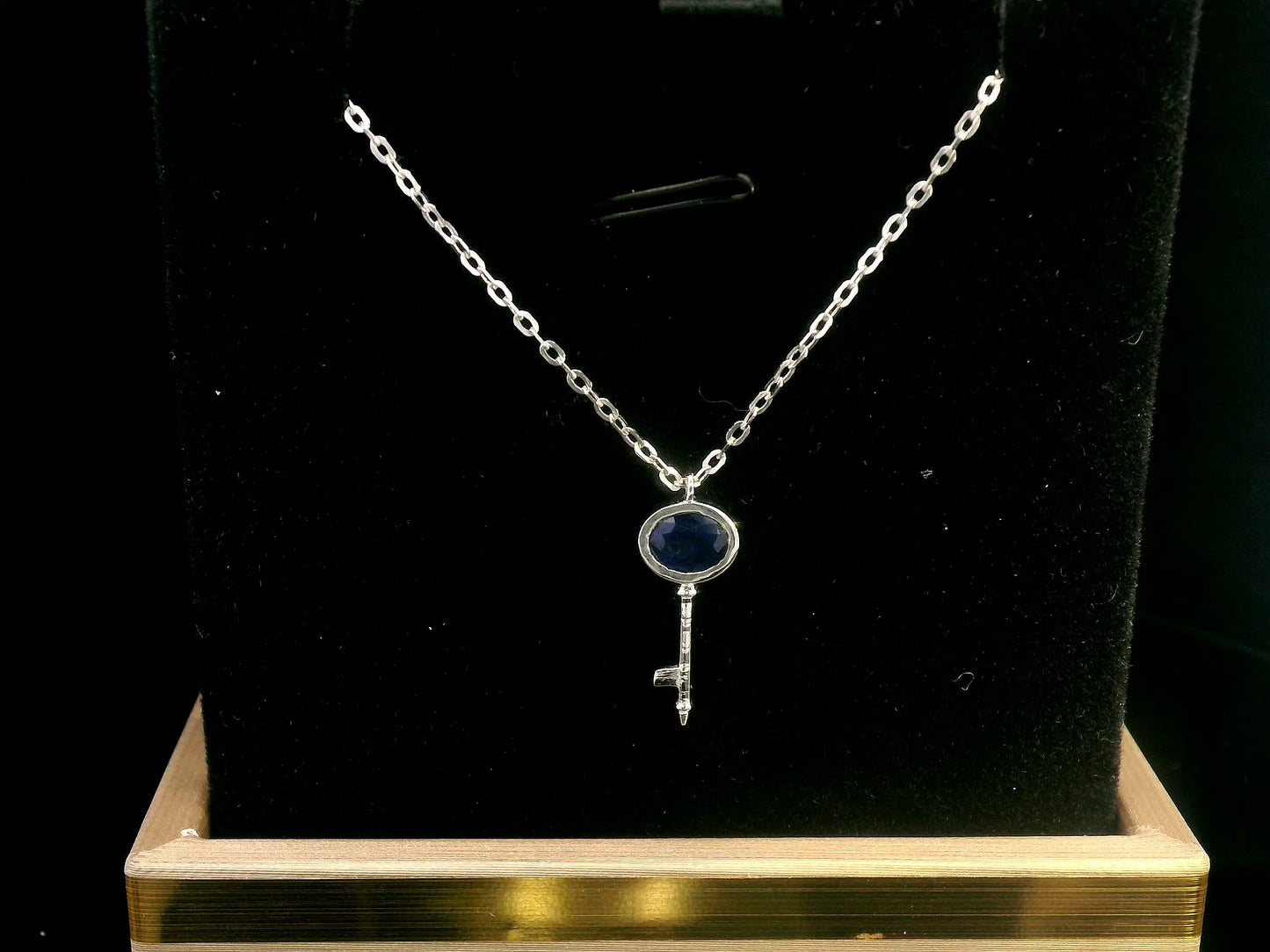 18K gold key pendant necklace with a 0.40ct natural sapphire in a bezel setting, complete with a delicate gold chain.