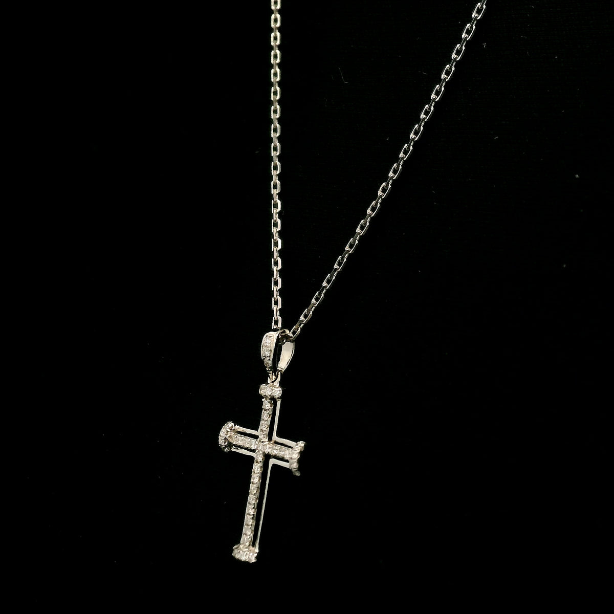 Diamond cross pendant in 18K white gold featuring an openwork design with round diamonds and diamond-accented ends.