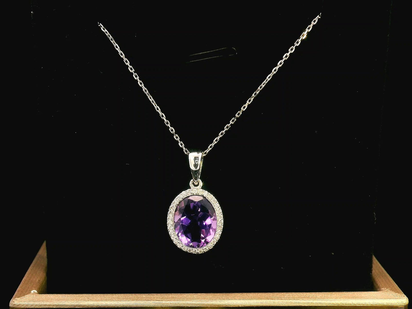18K yellow gold pendant featuring a 2.50-carat oval Amethyst with a delicate 0.11-carat diamond halo. Elegant and timeless.