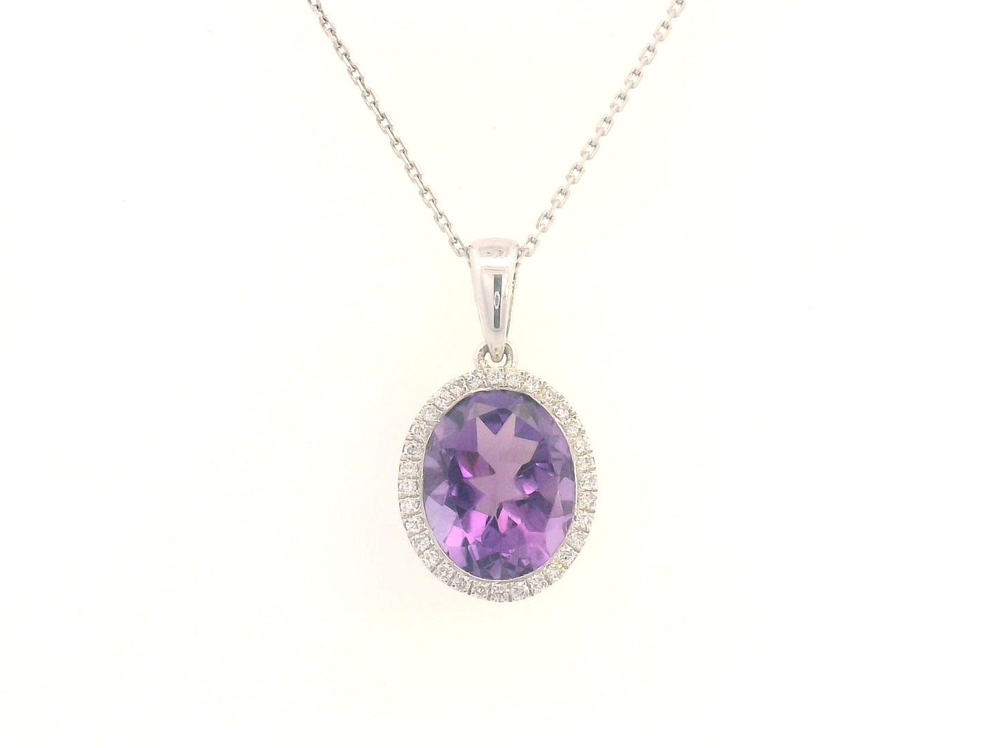 18K yellow gold pendant featuring a 2.50-carat oval Amethyst with a delicate 0.11-carat diamond halo. Elegant and timeless.