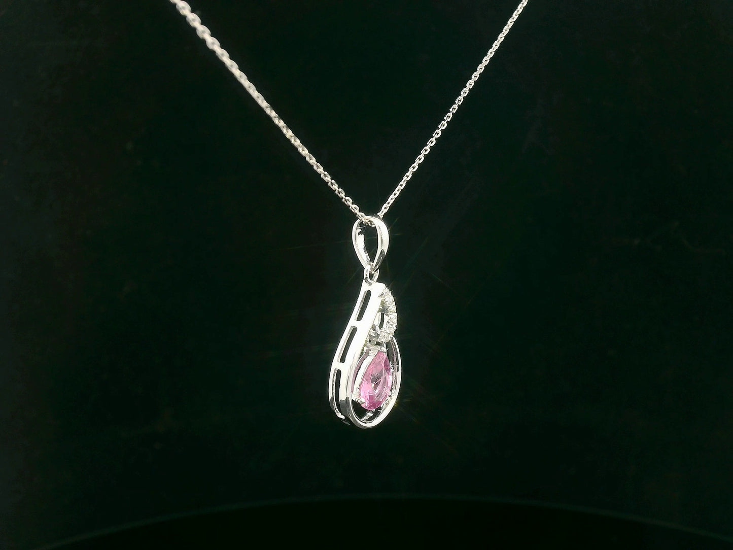 Side profile of pear-shaped pink sapphire pendant with diamond swirl design