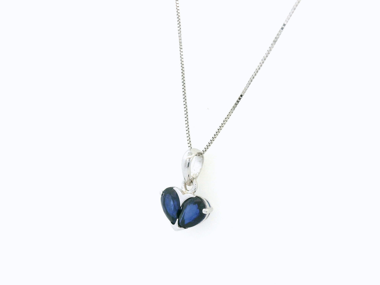 18K white gold heart pendant featuring two pear-cut blue sapphires forming a heart, Emirates Diamonds