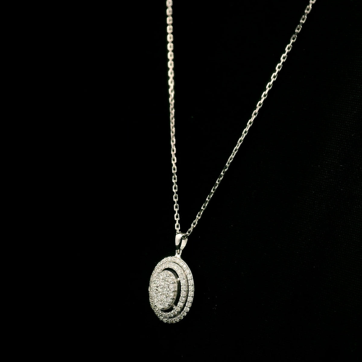 Oval diamond cluster pendant in 18K white gold with a central round diamond cluster and two diamond-set oval surrounds.