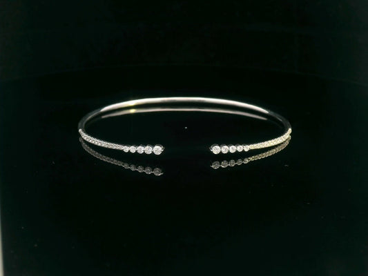 18K gold open diamond bangle bracelet with graduated diamonds, featuring a sleek and modern minimalist design.