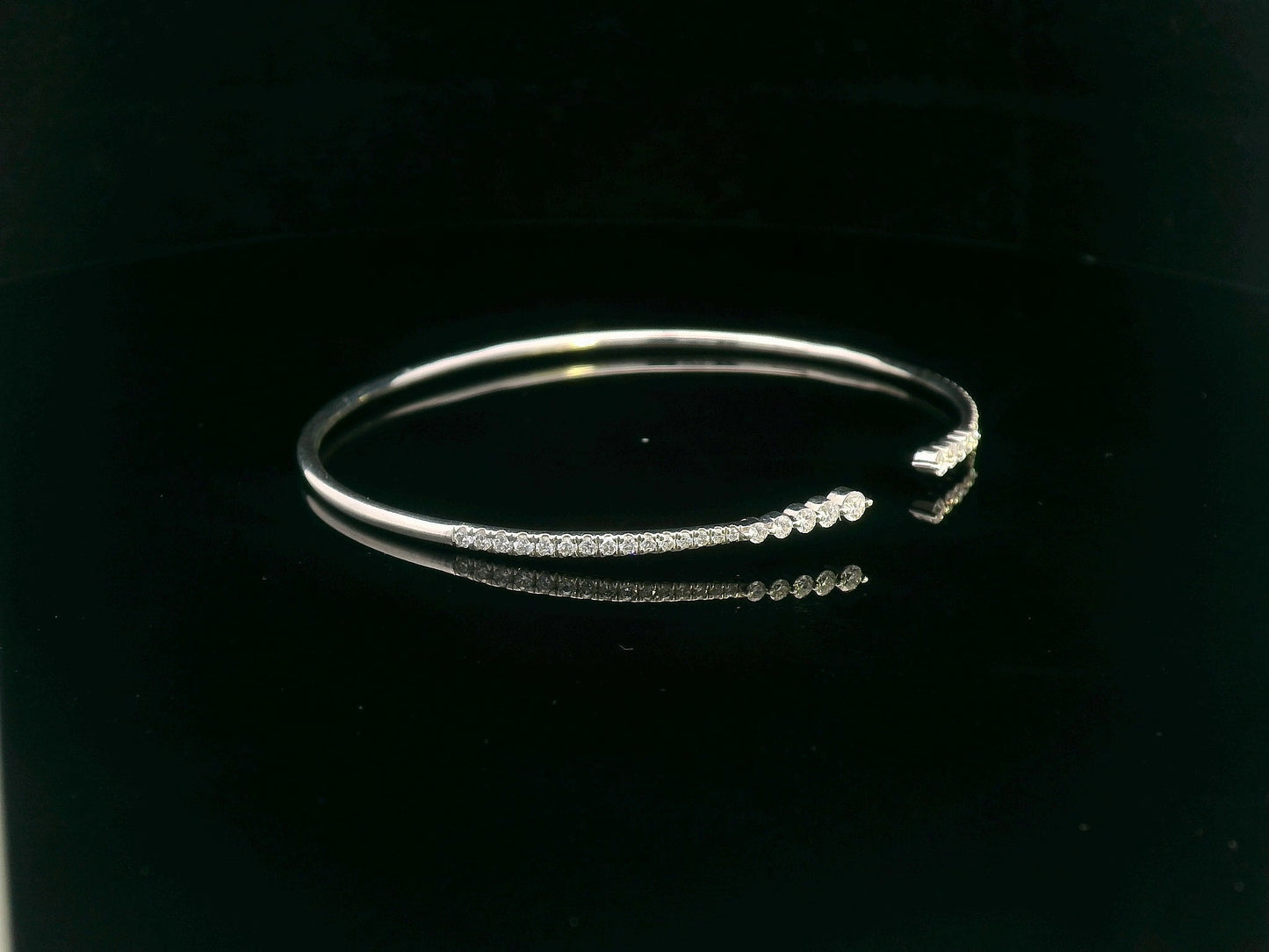 18K gold open diamond bangle bracelet with graduated diamonds, featuring a sleek and modern minimalist design.