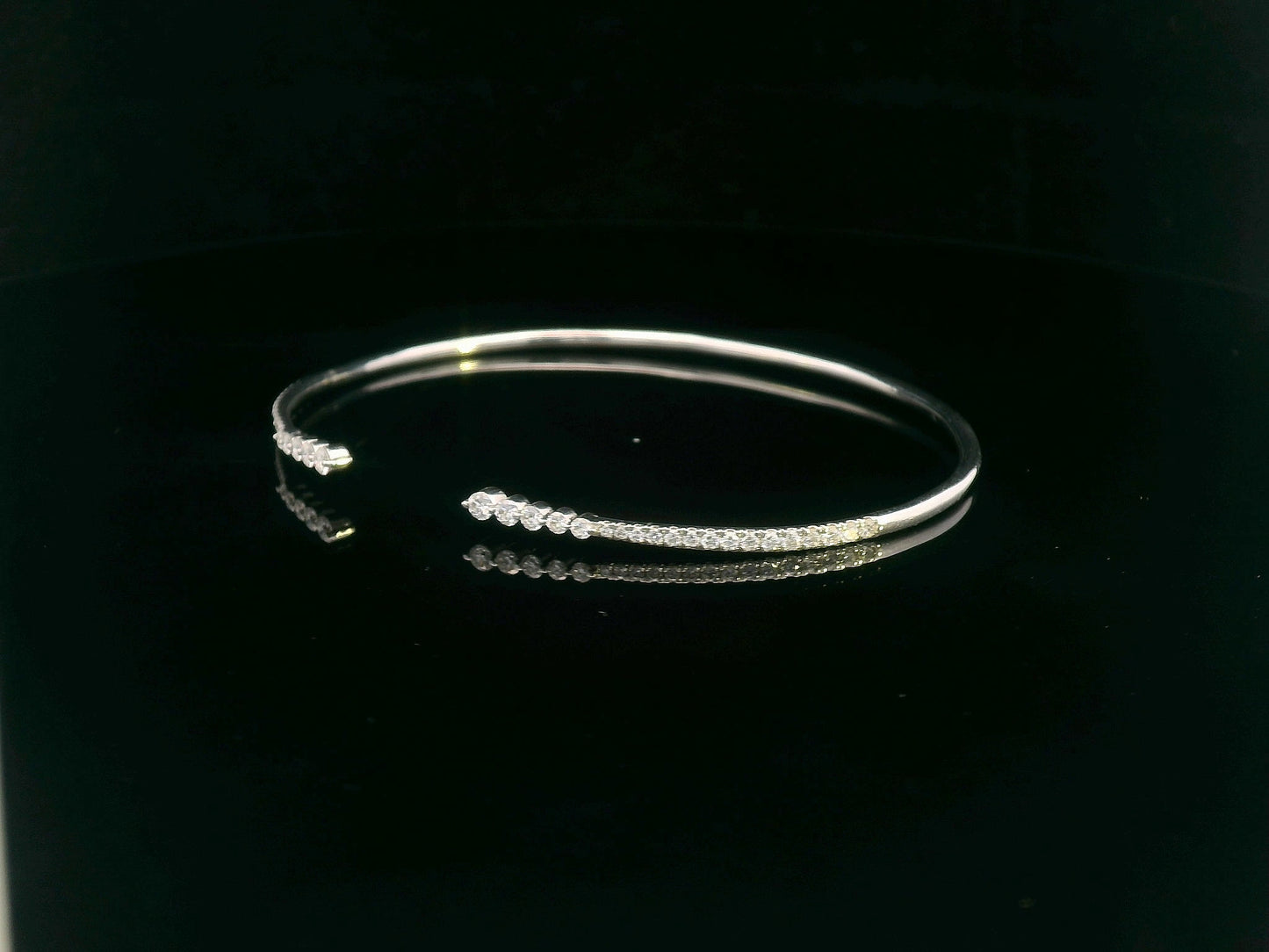 18K gold open diamond bangle bracelet with graduated diamonds, featuring a sleek and modern minimalist design.