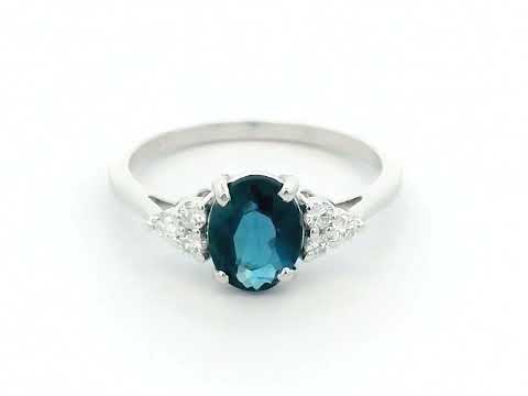 18K gold London Blue Topaz and diamond ring with a 1.30-carat oval-cut gemstone and 0.17 carats of round diamonds in a classic setting. Perfect blue gemstone ring for women.