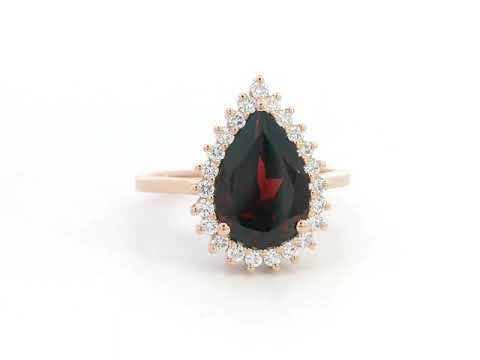 18K rose gold ring with pear-shaped garnet and starburst diamond halo setting