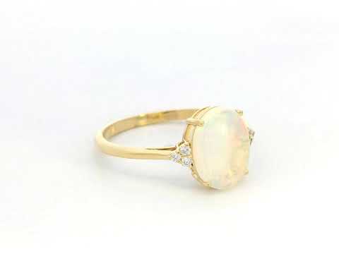 18K yellow gold ring with oval opal center flanked by accent diamonds.