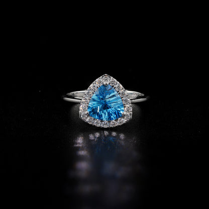 18K white gold ring with a triangular bright blue topaz surrounded by round diamonds and polished split-shank shoulders.
