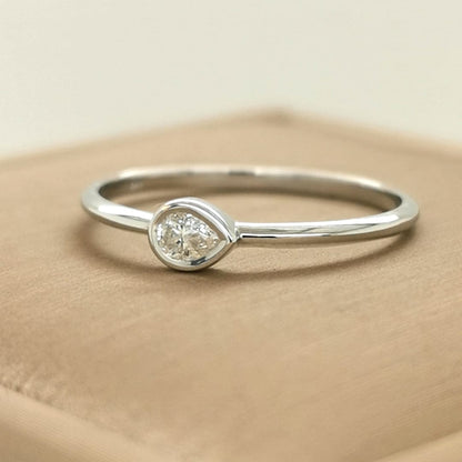 This Solitaire Ring Is Set With A Single Pear-Shaped Diamond.  A Marvel Held Delicately In A Bezel Setting. Crafted To Perfection, This Ring Showcases The Breathtaking Beauty Of A Single, Exquisite Pear-Shaped Diamond, Chosen For Its Unique Symmetry And Brilliance. The Bezel Setting Not Only Provides A Secure Embrace For The Diamond But Also Accentuates Its Natural Radiance, Allowing Light To Play Upon Every Facet.
