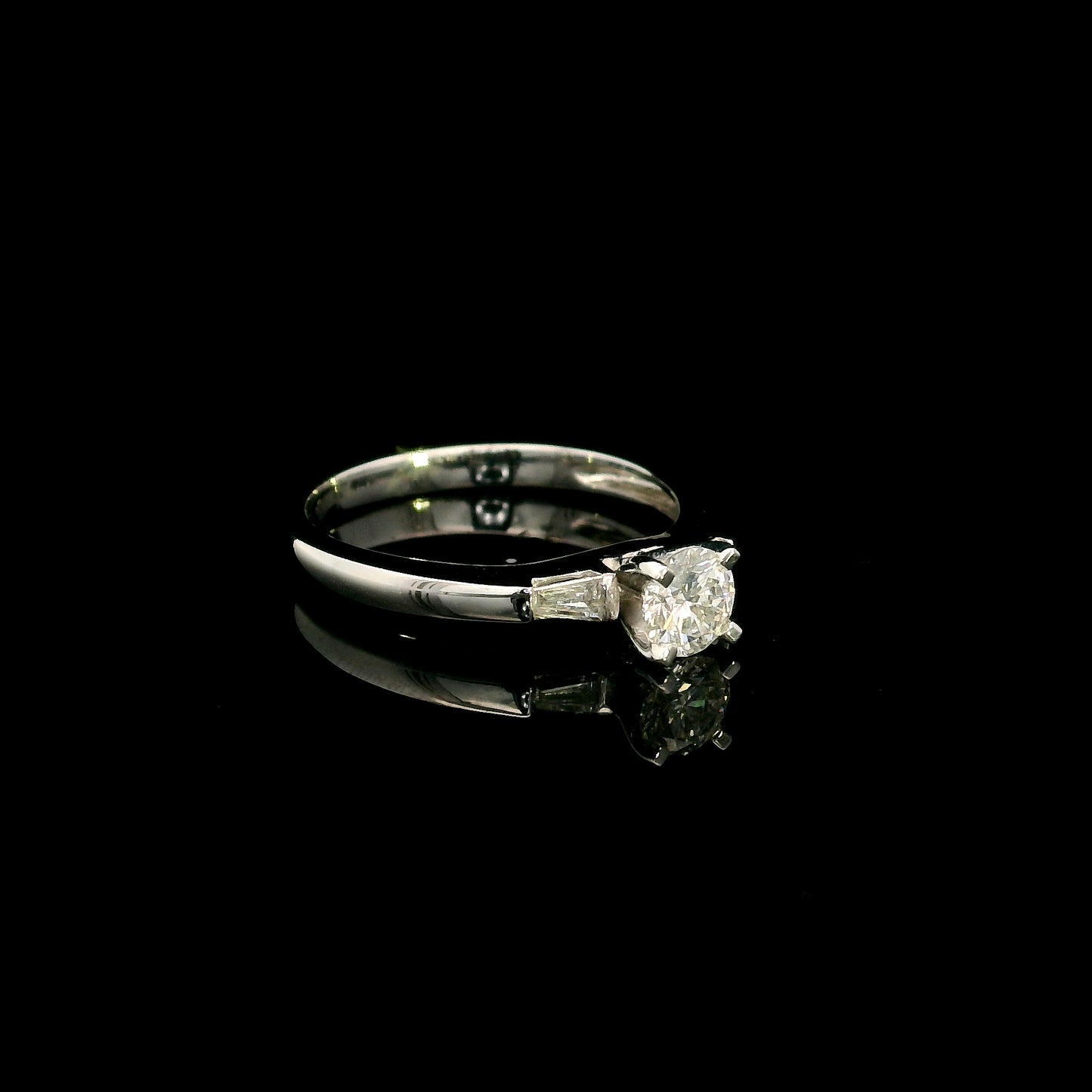 18K white gold round diamond solitaire ring with tapered baguette side diamonds and a classic elegant design.