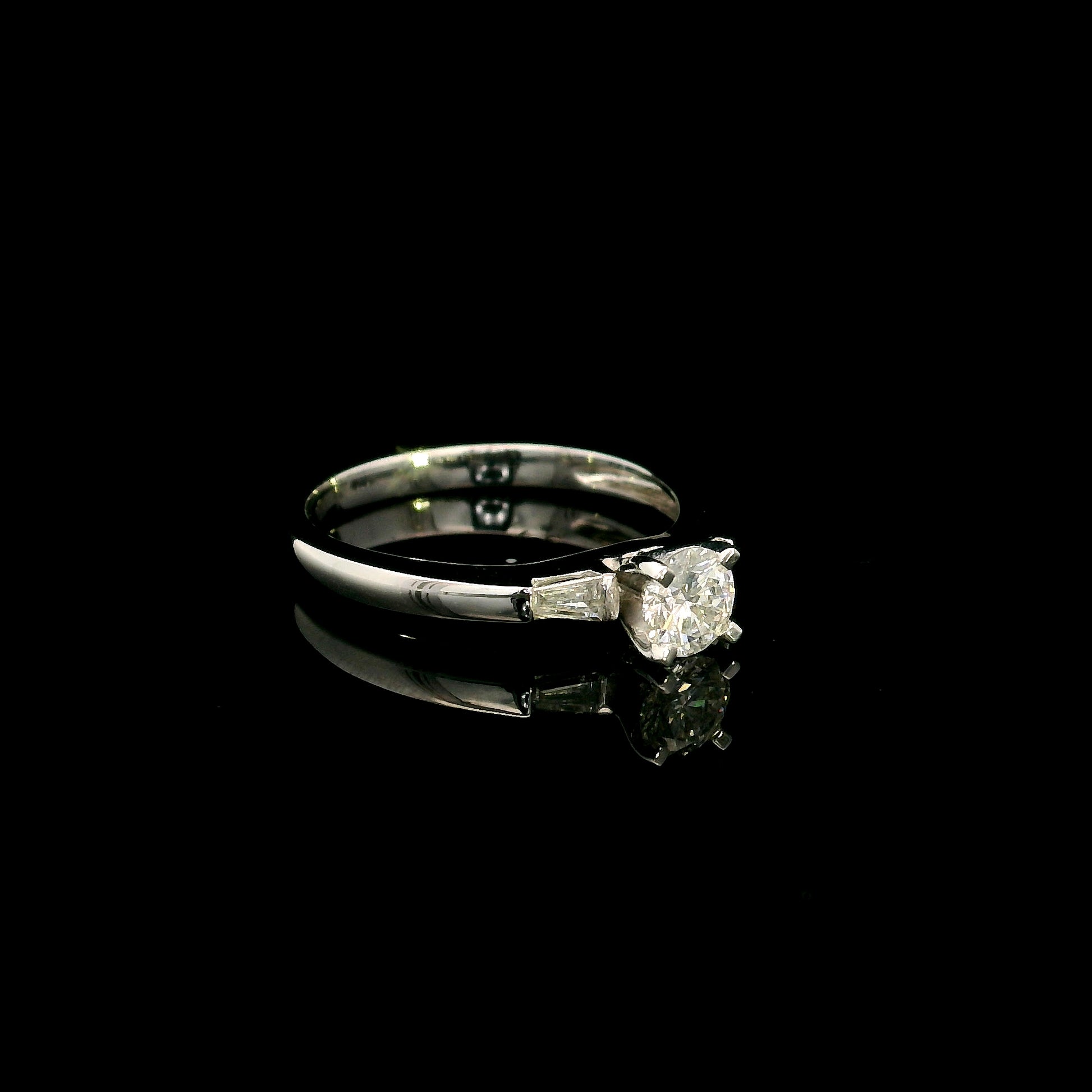 18K white gold round diamond solitaire ring with tapered baguette side diamonds and a classic elegant design.