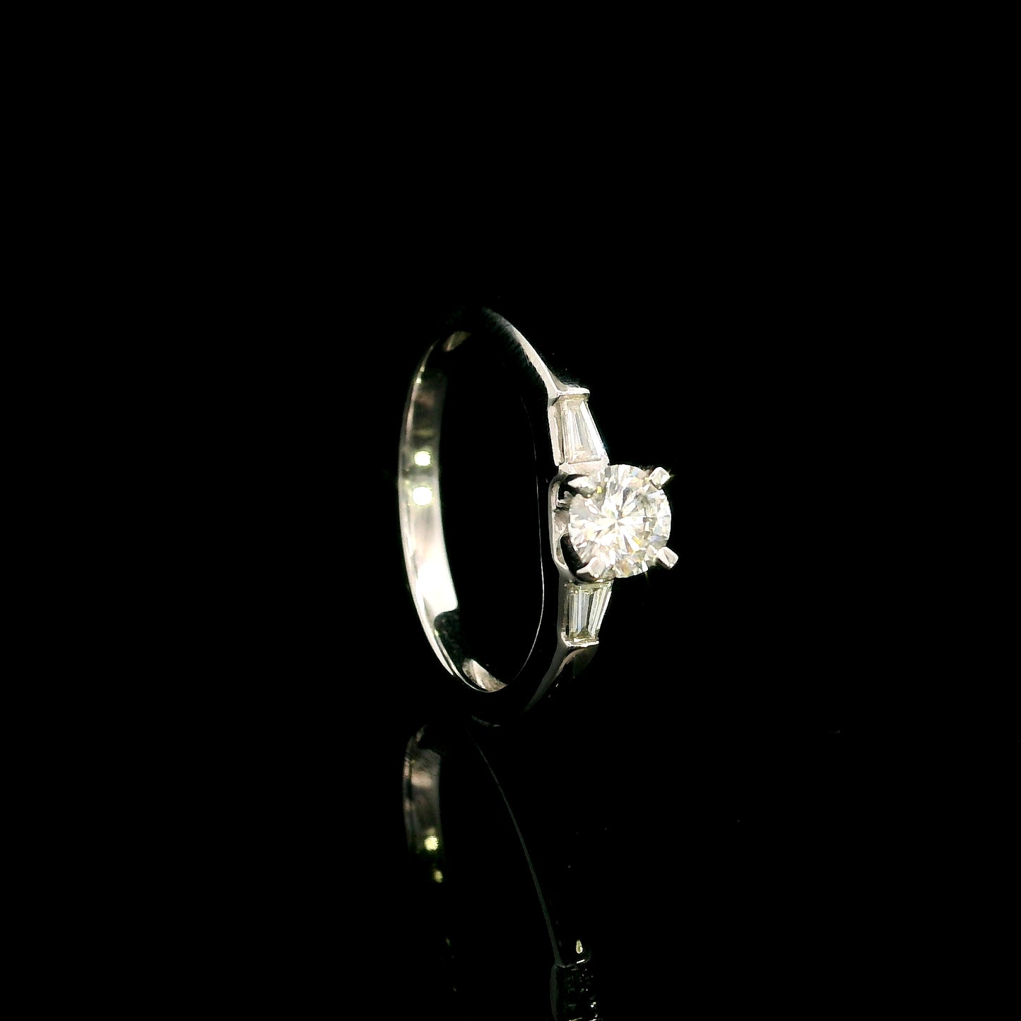 18K white gold round diamond solitaire ring with tapered baguette side diamonds and a classic elegant design.