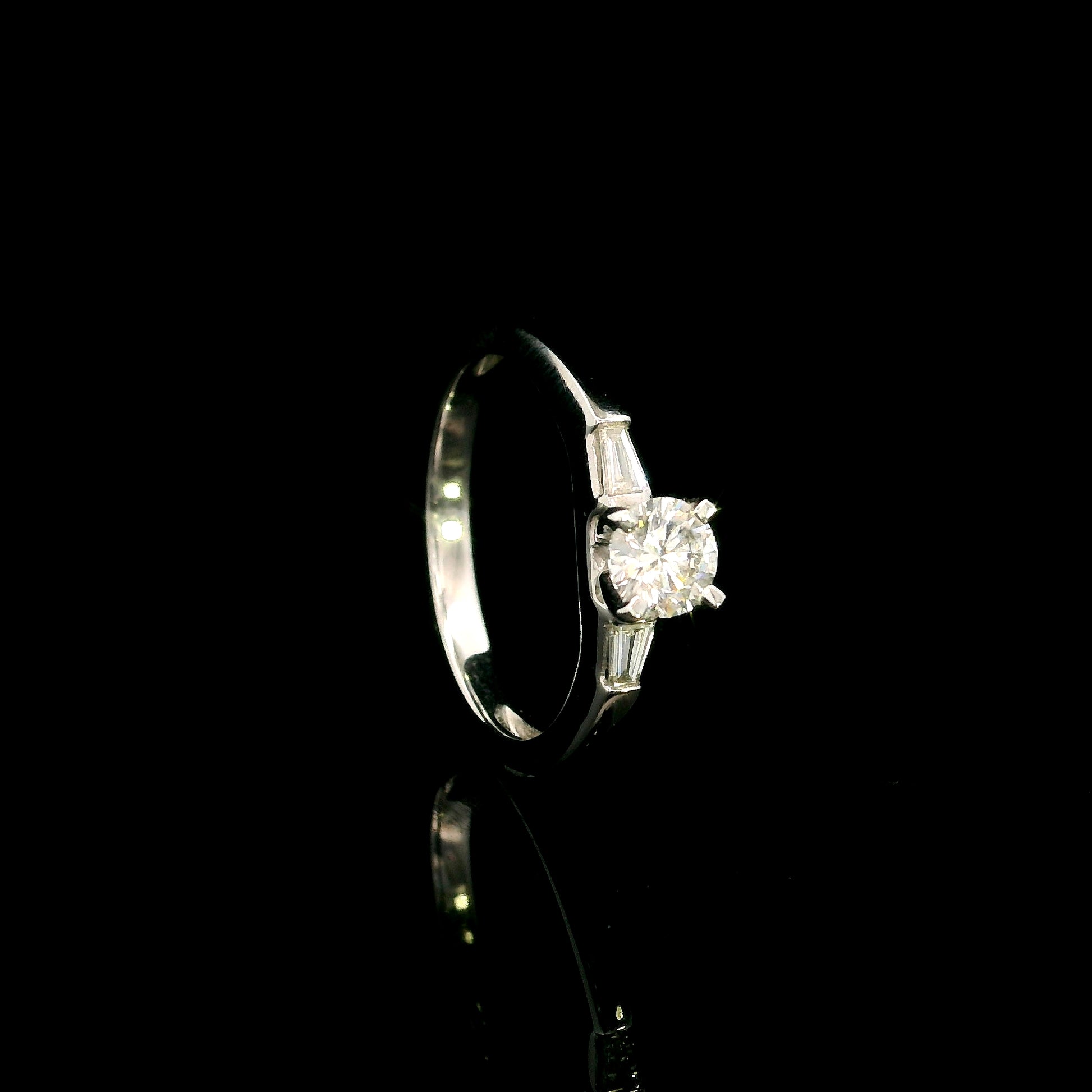 18K white gold round diamond solitaire ring with tapered baguette side diamonds and a classic elegant design.
