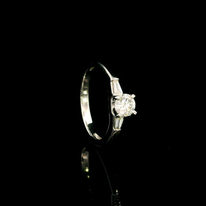 18K white gold round diamond solitaire ring with tapered baguette side diamonds and a classic elegant design.