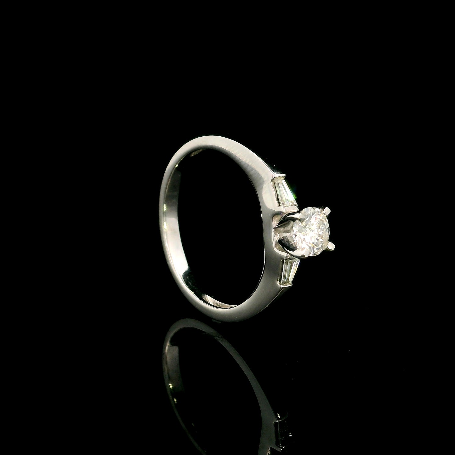 18K white gold round diamond solitaire ring with tapered baguette side diamonds and a classic elegant design.