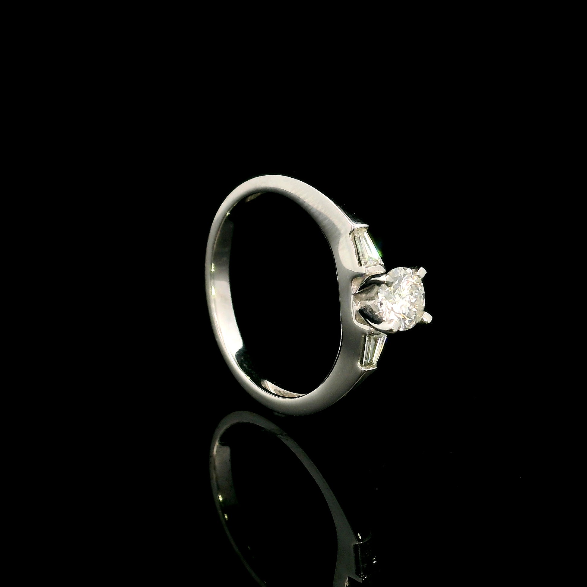 18K white gold round diamond solitaire ring with tapered baguette side diamonds and a classic elegant design.