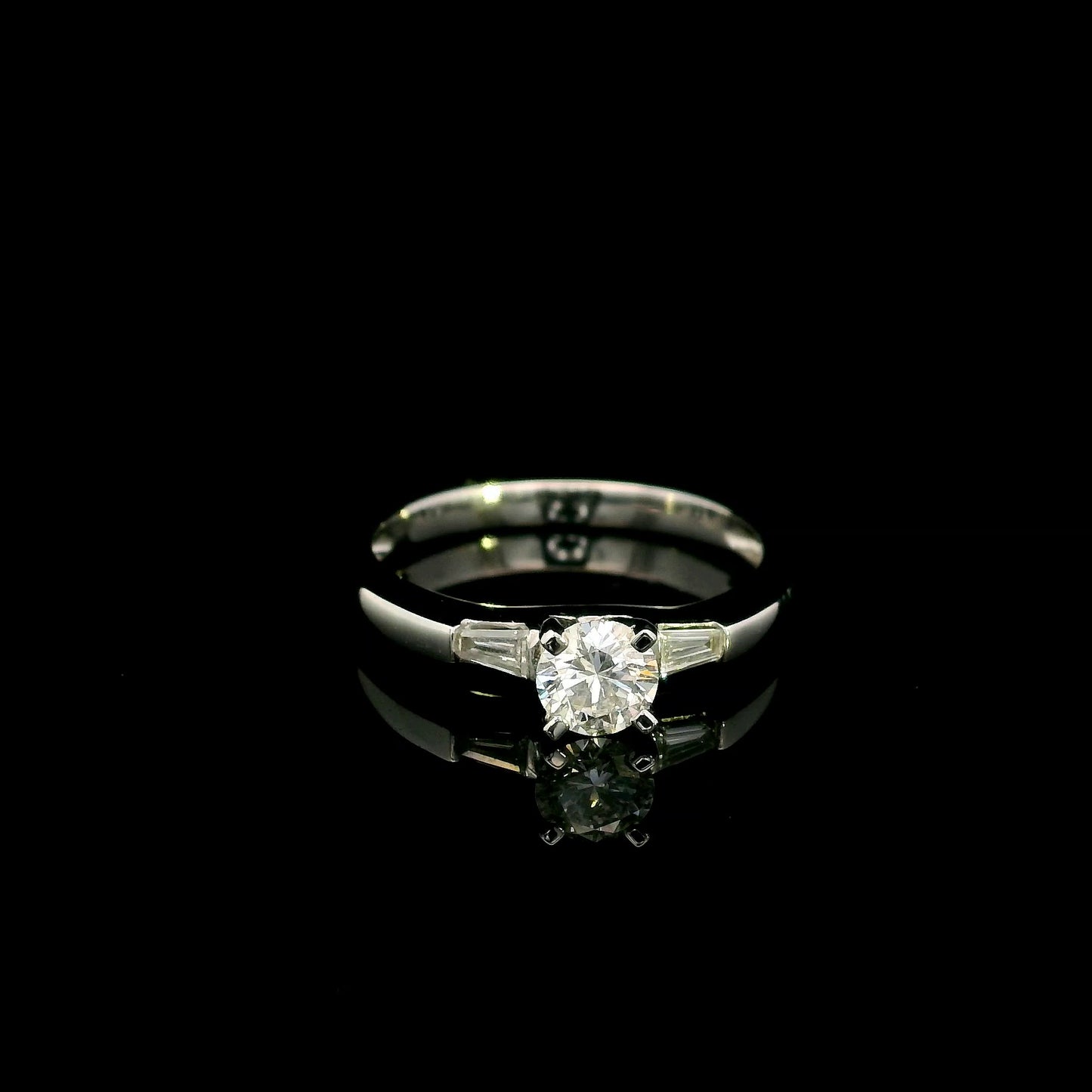 18K white gold round diamond solitaire ring with tapered baguette side diamonds and a classic elegant design.
